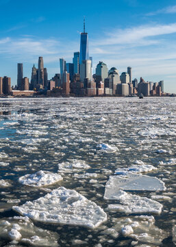 Lower Manhattan skyline with World Trade Center skyscrapers viewed across the frozen Hudson River covered with floating ice floes during winter, New York City, USA