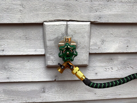 New outdoor home water faucet installed on exterior wood cedar sliding
