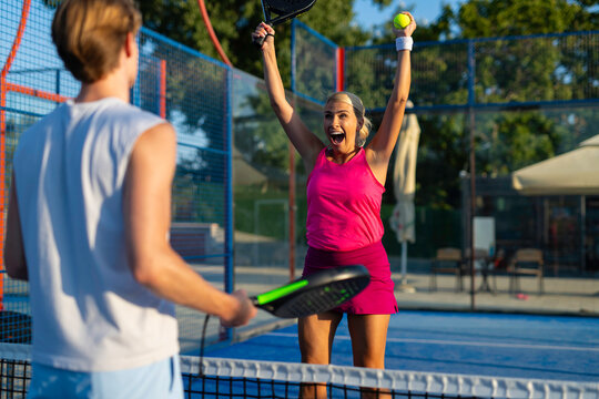 Woman celebrating victory playing padel on outdoor court