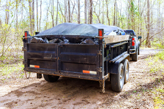 Dump trailer parked on dirt road in wooded area