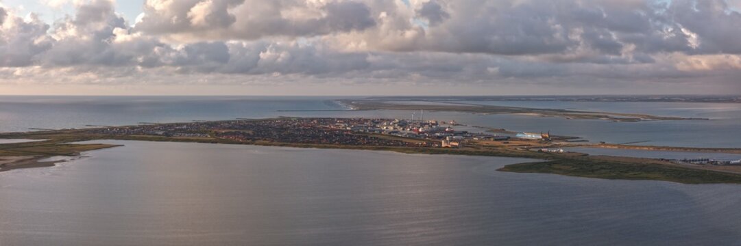 Aerial view of the harbor town of Thyboron, situated where the Limfjord meets the North Sea, featuring industrial port facilities, coastal landscape, and calm waters in Thyboron, Denmark.