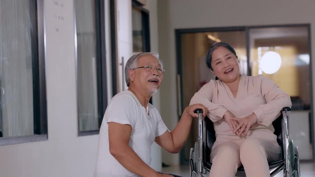 Senior man wheelchair woman caregiver clinic support happy indoor elderly couple medical corridor mobility aid healthcare rehabilitation lifestyle calm smiling together