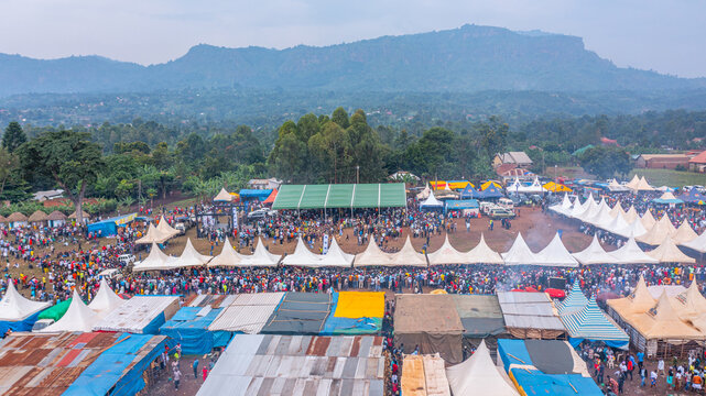 Aerial view of the Bamasaaba Culture Centre Mutoto during a festival, with numerous white tents, a large crowd, and lush green hills in the background in Mbale, Eastern Region, Uganda.