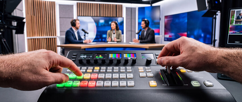 Broadcast studio control panel with audio mixer and technicians producing live video interview