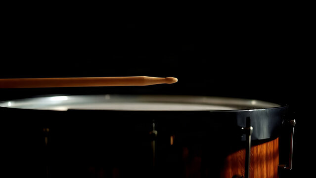 Drumstick poised just above the skin of a timpani drum.