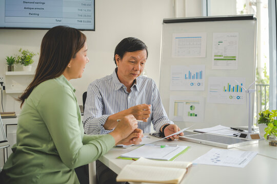 A diverse group of business professionals working together in a modern office, analyzing environmental data and charts to develop eco-friendly, sustainable corporate strategies.