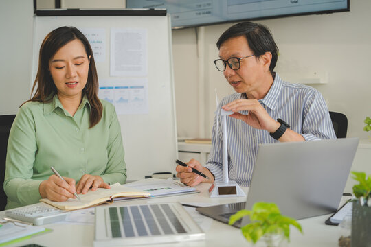 A diverse group of business professionals working together in a modern office, analyzing environmental data and charts to develop eco-friendly, sustainable corporate strategies.