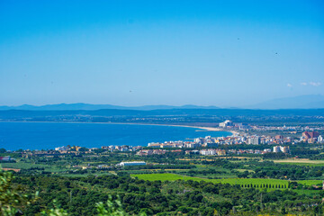 Fototapeta premium Mediterranean Coastal City and Green Hillside Overlooking Shoreline in Cadaqués, Costa Brava, Spain
