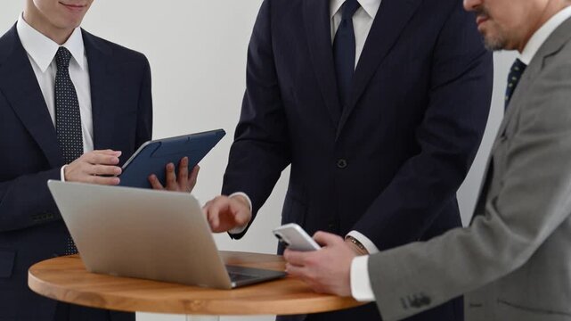 ノートパソコンとタブレットを使って打ち合わせを行う30代と50代の日本人ビジネスマン