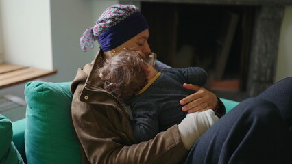 Fototapeta premium Mother recovering from cancer embracing toddler on sofa at home, family support moment highlighting healing, resilience, attachment and emotional strength