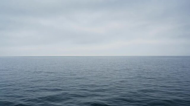 Calm ocean water under a cloudy sky with a distant horizon