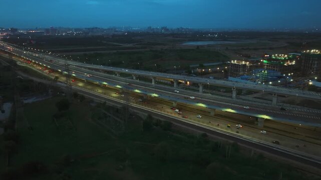 Aerial view of highway with flowing traffic and illuminated street lights at dusk in Gurgaon, Haryana, India.