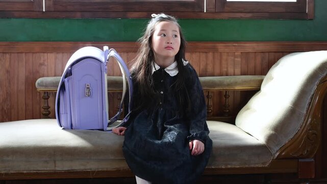 ソファに座って物憂げな表情を見せる日本人の女の子