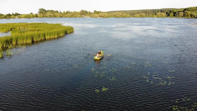 Couple rowing a boat together on a peaceful lake in the countryside at sunset