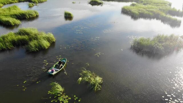 Couple rowing a boat together on a peaceful lake in the countryside at sunset
