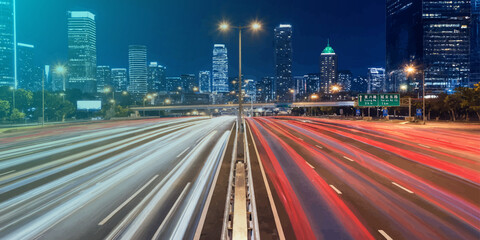 City highway at night with blurred traffic light streaks exposure transportation downtown metropolis infrastructure vehicles movement velocity nighttime skyscrapers waypoint exterior © KHADIZA
