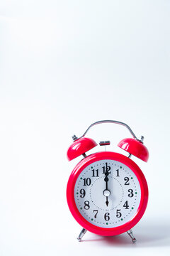 The classic red alarm clock is isolated on a white background