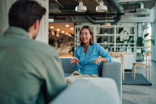 Asian businesswoman discussing with male colleague in modern office, having a serious conversation during a meeting