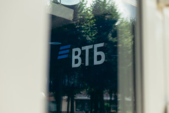 The sign of VTB bank is prominently displayed on a building window in a busy urban area.