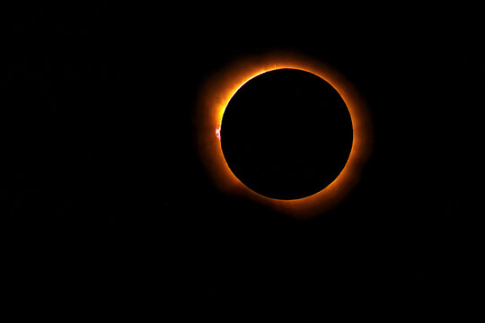 Total solar eclipse showing the diamond ring effect with solar prominences and corona visible against a dark space background during totality