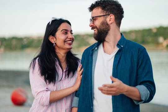 Multicultural couple having an outdoors conversation, laughing and sharing a happy moment together