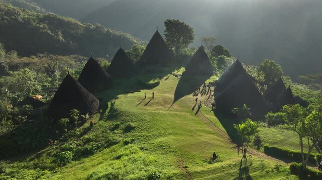 Aerial view of Waerebo Village with traditional conical houses on a lush green mountain ridge in Satar Mese Barat, East Nusa Tenggara, Indonesia.