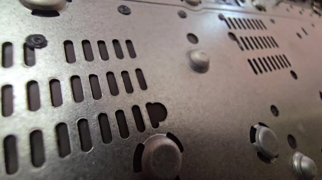 Close-up of a metal laptop chassis case with ventilation slots and internal mounting standoffs.