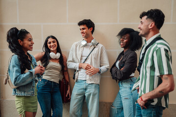 Fototapeta premium Group of diverse smiling young friends talking and laughing outdoors, connecting in an urban street setting