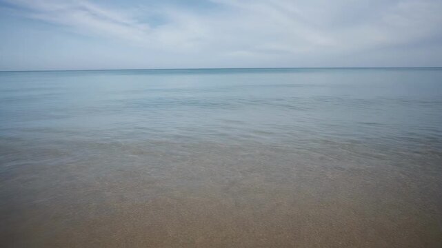 Calm ocean water under a cloudy sky with gentle waves near the shore