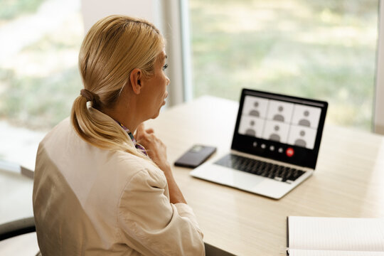 Woman participating in virtual meeting from small office, focused and engaged