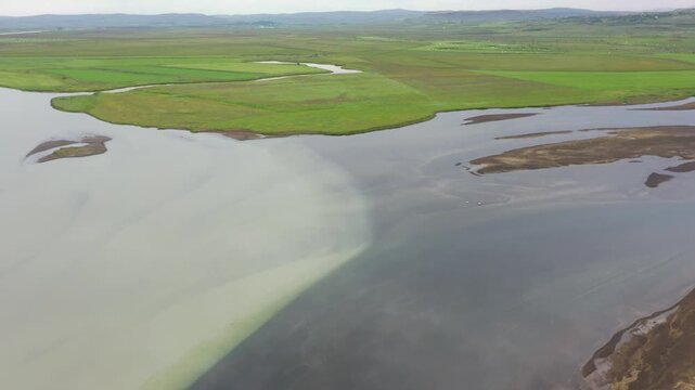 Water from glacier and clear mountain water meet in the river Stora Laxa, Iceland