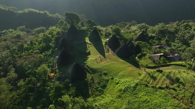 Aerial view of Waerebo Village with traditional conical houses nestled in the lush green mountains of Satar Mese Barat, East Nusa Tenggara, Indonesia.