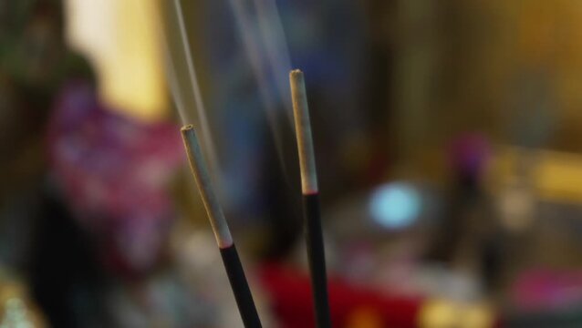 Burning incense sticks with glowing embers and rising smoke, spiritual background