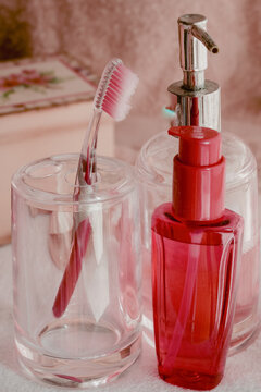 Personal care products, including a toothbrush and liquid soap dispenser, presenting a pastel pink morning routine setup for daily self care and oral hygiene