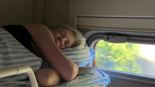 Elderly female traveler sleeping on train upper bed during morning journey, tourism industry, rail trip promotion, peaceful transit moment.