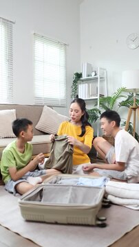 Mother and children packing clothes into suitcase for family vacation