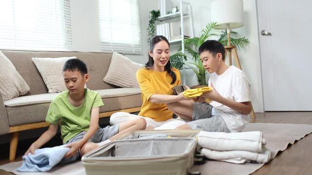 Mother and children packing clothes into suitcase for family vacation
