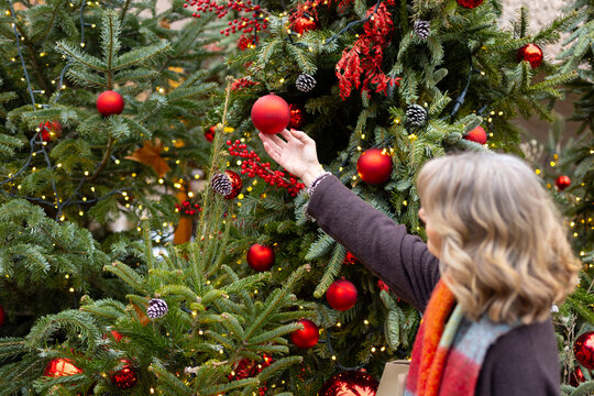 Woman decorating christmas tree with red ornament
