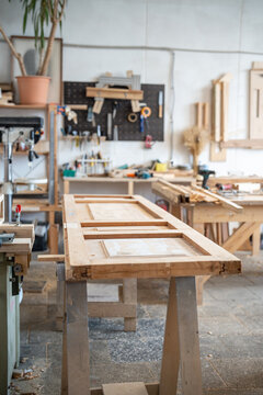 Renovation process in restoration workshop, antique wooden door lying at workbench in carpentry, professional handwork reconstruction and handmade repair service, workstation in woodworking shop.