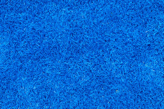 Top view closeup of bright blue artificial turf or synthetic grass surface, suitable as a background, sports field carpet, or decorative texture.