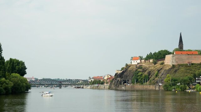 Historic Vysehrad fortress wall stands on a rocky cliff along the Vltava River in Prague city. Scenic architectural landscape showcases famous landmark for European travel and Czech tourism.