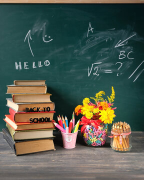 back to school concept. school stationery, flowers bouquet and stack of learning books on table against chalkboard. symbol of beginning of the school year, Knowledge Day, education,1 September