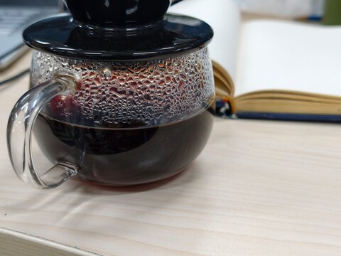 Close-up of hot brewed coffee in a glass server with condensation on a wooden table. Perfect for artisanal coffee concept.