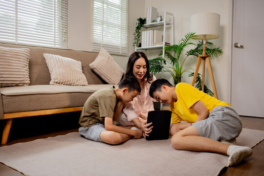 Mother teaching music to her children while playing guitar at home