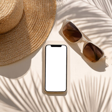 Summer travel flat lay with smartphone sunglasses straw hat and tropical palm shadows