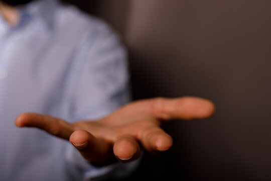 A person extends their open palm forward, offering or seeking assistance.
