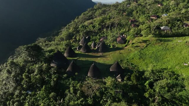 Aerial view of the traditional conical houses of Waerebo Village nestled in the lush green mountains of Satar Mese Barat, East Nusa Tenggara, Indonesia.