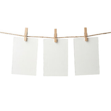 Three blank paper cards hanging on a clothesline with wooden pins