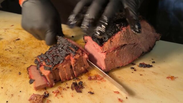 A culinary professional uses a sharp knife to carve thick slices of smoked beef brisket with a dark seasoned bark on a large commercial cutting board in a professional kitchen environment