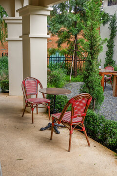 Luxury chair and wooden table set in english garden on a sunny day,outdoor seating for restaurant or cafe,Near paver patio with sitting area and small garden in forest.